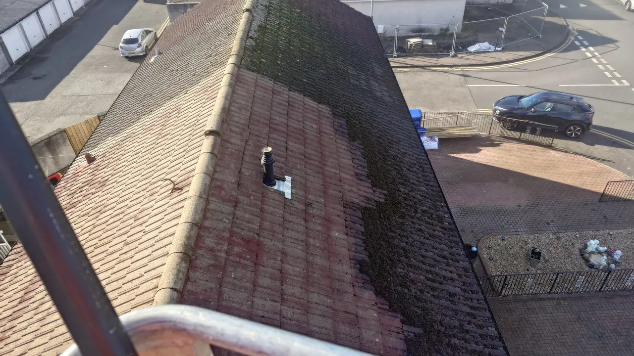 Roof cleaning worker scraping moss off large roof